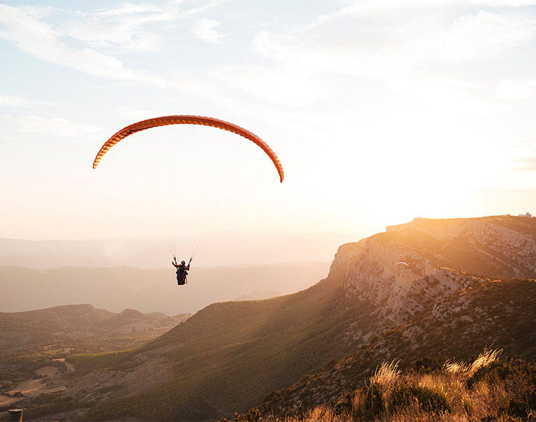 paraglider flying on mountains during sunset paraglider flying on mountains during sunset